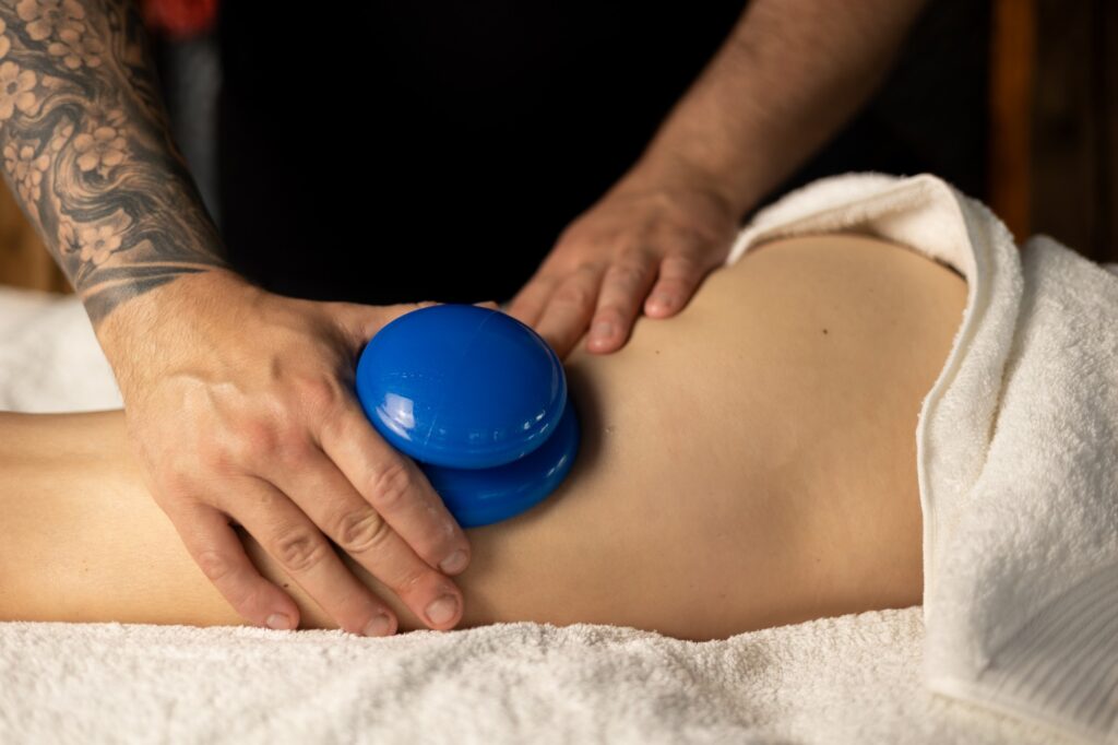 Antycellulitowy masaż bańką chińską - terapeuta przesuwa silikonową bańkę po ciele